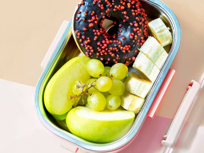 catering-food-prepared-in-storage-container-with-compartment-with-doughnut-apple-banana-grape.jpg